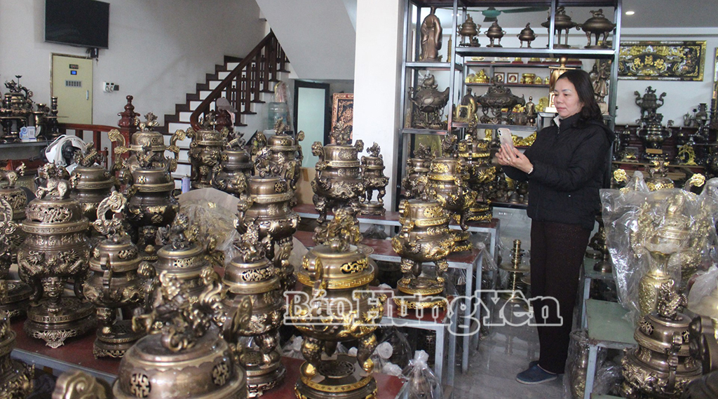 Bà Đỗ Thị Thắm, chủ cơ sở đồ đồng mỹ nghệ Hồng Thắm chụp ảnh sản phẩm gửi cho khách hàng.