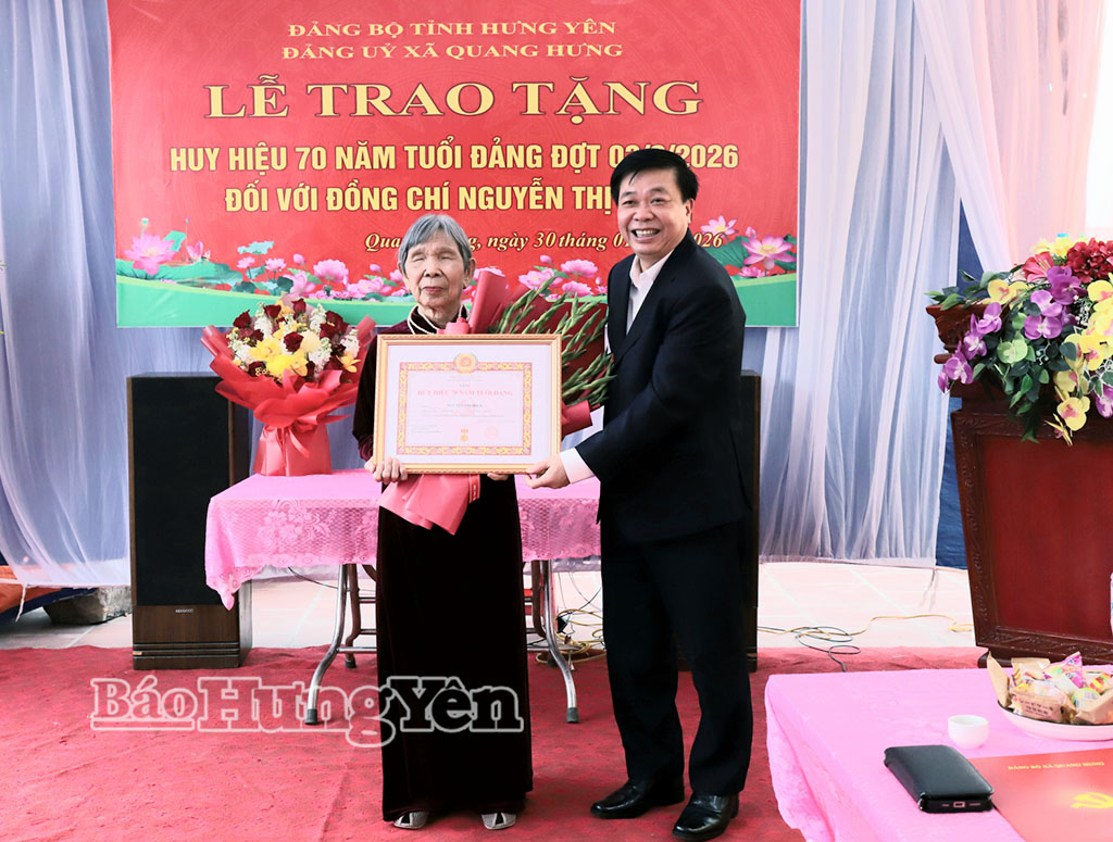 Đồng chí Nguyễn Quang Hưng, Ủy viên Ban Thường vụ Tỉnh ủy, Chủ nhiệm Ủy ban Kiểm tra Tỉnh ủy trao Huy hiệu 70 năm tuổi Đảng và tặng hoa chúc mừng đảng viên Nguyễn Thị Hiện. Ảnh: Phương Châm