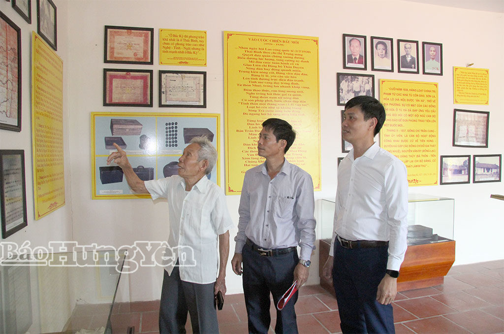 Cựu chiến binh Phạm Văn Cư, thôn Vị Giang, xã Hồng Minh (đứng thứ nhất bên tay trái) cùng cán bộ xã xem lại tư liệu thời chiến tại di tích lịch sử cách mạng Trường Vị Sĩ. 