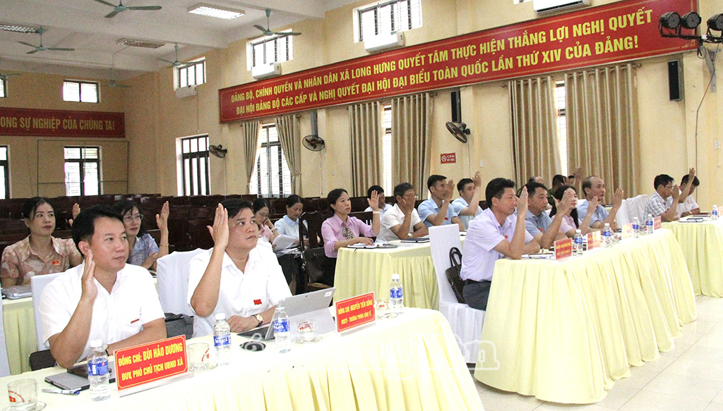 Các đại biểu HĐND xã Long Hưng biểu quyết thông qua Nghị quyết về việc thực hiện Đề án sắp xếp, tổ chức lại thôn, tổ dân phố trên địa bàn xã. Ảnh: Thanh Thủy 