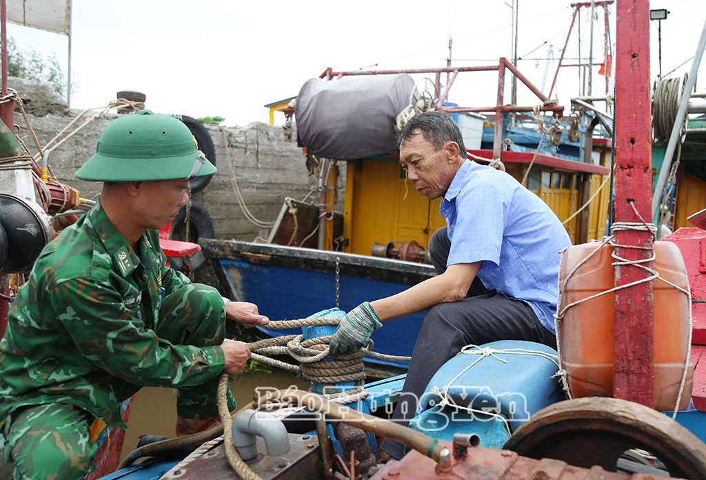 Cán bộ Trạm kiểm soát biên phòng Cửa Lân hỗ trợ ngư dân chằng buộc phương tiện an toàn ứng phó với bão.